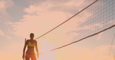 Plaj voleybolu oynayan atletik kız havada atlar ve güzel bir yaz akşamı net üzerinden topa vurur. Beyaz kadın bir puan