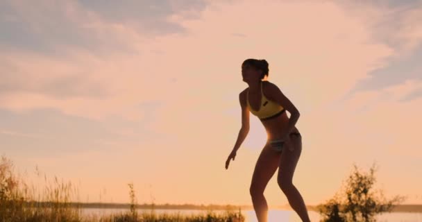 セクシーな女の子バレーボール選手は、ネットの近くにボールを渡し、スローモーションで日没時にボールを打ちます — ストック動画