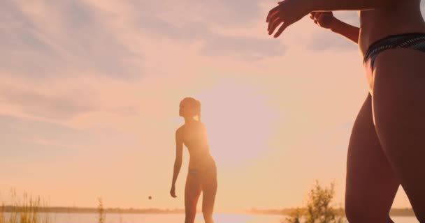 Beachvolleyball-Mädchen schlagen den Ball bei Sonnenuntergang im Sand in Zeitlupe. — Stockvideo