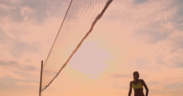 Las chicas del partido de voleibol playa golpean la pelota en cámara lenta al atardecer en la arena . — Vídeos de Stock