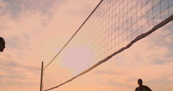 若い女子バレーボール選手は、晴れた夏の夜にネット上でボールを渡し、スパイクします。日没時にビーチバレーをプレイするフィット白人の女の子 — ストック動画