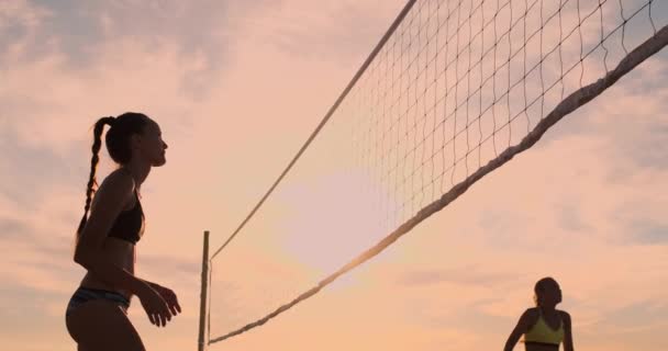 비치 발리볼을 하는 육상 소녀는 공중에서 점프하고 아름다운 여름 저녁에 그물을 통해 공을 친다. 백인 여자 점수 a 포인트 — 비디오