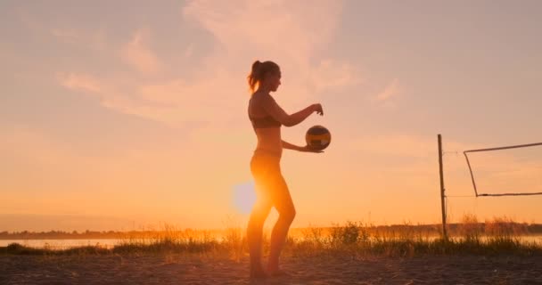 Chica atlética jugando voleibol playa salta en el aire y golpea la pelota sobre la red en una hermosa noche de verano. Mujer caucásica puntuación de un punto — Vídeos de Stock