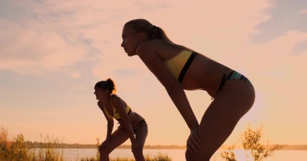 Chica atlética jugando voleibol playa salta en el aire y golpea la pelota sobre la red en una hermosa noche de verano. Mujer caucásica puntuación de un punto — Vídeos de Stock