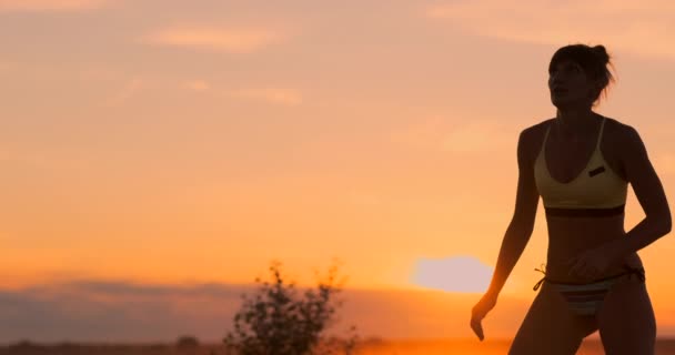 Krásná volejbalové děvče v bikinách při západu slunce po jejím spoludružce během zápalu, — Stock video