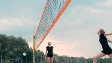 Plajda voleybol oynayan genç kadın atak gerçekleştiren bir takım topa vurdu. Yavaş çekimde kız topa vurur ve net üzerinden bir saldırı yürütmek
