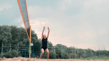 Profesyonel Plaj Voleybolu Turnuvasında Yarışan Kadınlar. Bir defans oyuncusu 2 kadın uluslararası profesyonel plaj voleybolu sırasında bir atış durdurmak için çalışır