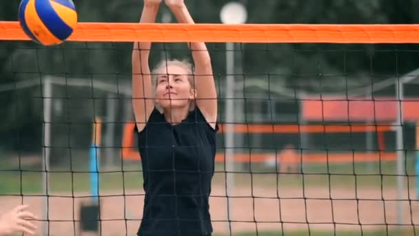 Cuatro jugadores de voleibol niñas juegan en la playa en el verano participando en el torneo en cámara lenta en la arena . — Vídeos de Stock