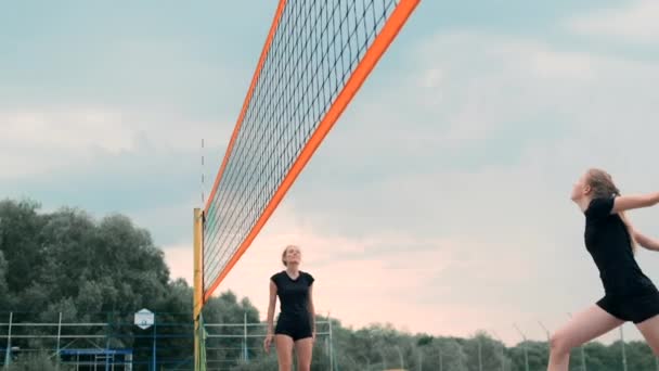 Jonge vrouw volleyballen op het strand in een team uitvoeren van een aanval op de bal. Meisje in Slow Motion slaat de bal op en voert een aanval uit via het net — Stockvideo