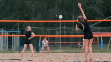 Kadın voleybol servisi. Plajda yavaş çekimde dururken voleybola hizmet etmeye hazırlanıyor kadın.