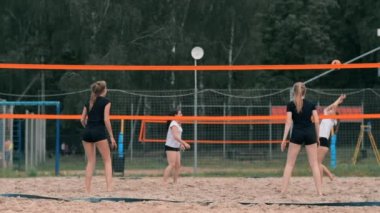 Dört kız voleybolcular kum üzerinde yavaş çekim de turnuvaya katılan yaz aylarında plajda oynamak.