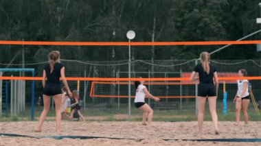 Kadın voleybol servisi. Plajda yavaş çekimde dururken voleybola hizmet etmeye hazırlanıyor kadın.