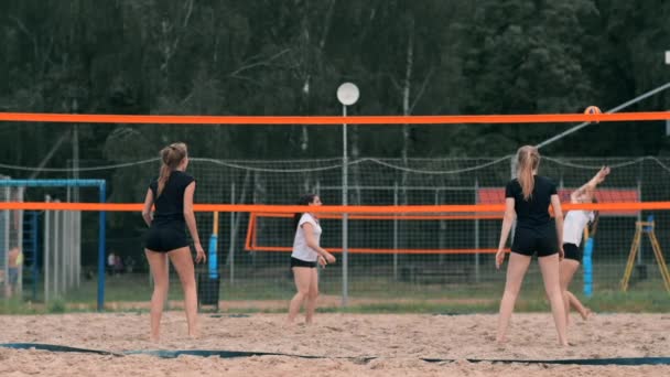 Négy lányok röplabda játékos játszik a strandon a nyáron részt vesz a versenyen lassítva a homokon. — Stock videók