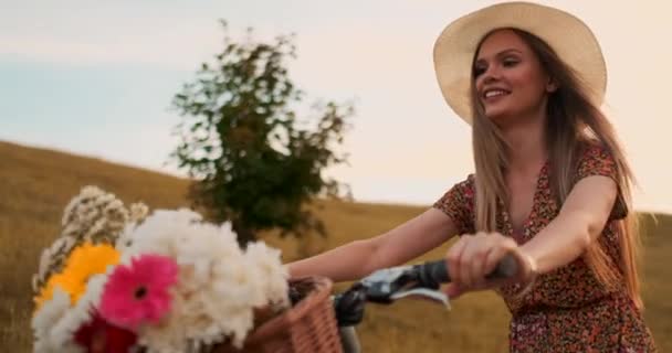 Middle plan är den blonda i hatten rider en cykel med blommor och leenden. — Stockvideo