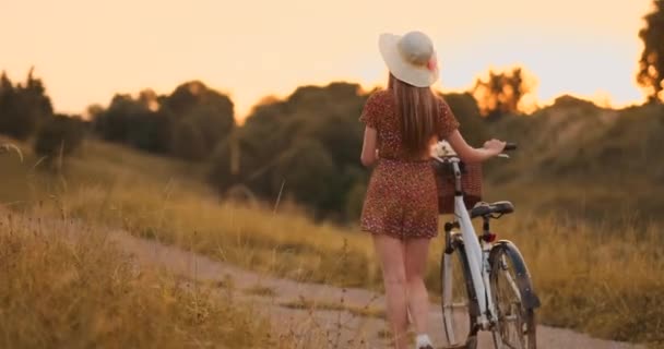 Powrót plan: Piękna Blondynka w sukni i retro rower chodzenie na drodze w polu letnim. — Wideo stockowe