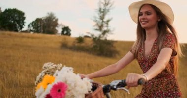 Orta plan şapka Blonde çiçekler ve gülümsüyor ile bir bisiklet sürmek olduğunu.