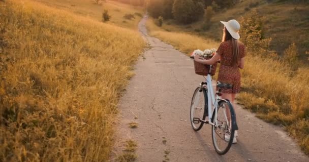 背计划：美丽的金发女郎在礼服和复古自行车走在夏天的田野的道路上. — 图库视频影像