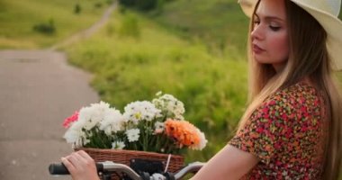 Bisikletli şapkalı bir kız arkasını döner ve kameraya gülümseyerek bakar..