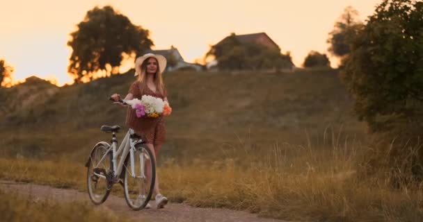 Jeune fille en robe marchant sur la route avec vélo et fleurs . — Video