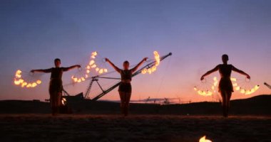 Profesyonel sanatçılar yavaş çekimde kum üzerinde bir yaz festivalinde bir ateş gösterisi göstermektedir. Sahilde gece yangın ile sirk çalışmadan dördüncü kişi akrobatlar.