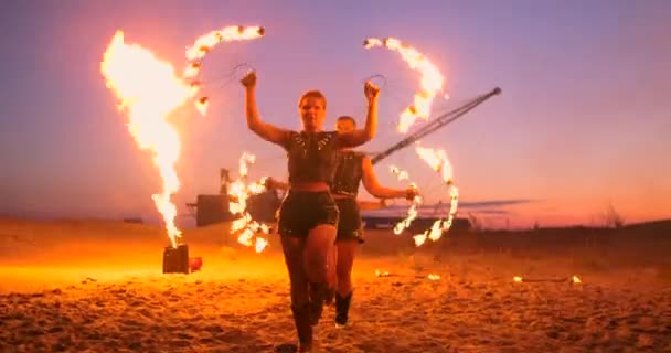 Professionele artiesten laten een vuurshow zien tijdens een zomer Festival op het zand in slow motion. Vierde persoon acrobaten van circus werken met vuur 's nachts op het strand. — Stockvideo