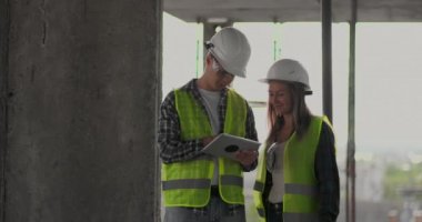 İki mühendis bir adam ve bir inşaat yerinde tablet bilgisayar ile bir kadın binanın inşaat planını kınaz