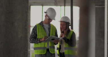 İnşaat sitesi takım veya mimar ve kurucu veya işçi kask ile bir iskele inşaat planı veya plan veya kontrol listesi üzerinde tartışmak.