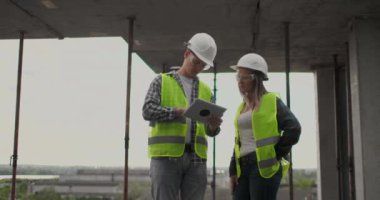 İnşaat sitesi takım veya mimar ve kurucu veya işçi kask ile bir iskele inşaat planı veya plan veya kontrol listesi üzerinde tartışmak.