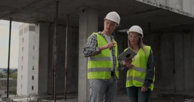 Mühendisler veya mimarlar inşaat planına bakarak şantiyede bir tartışma var. contre jour. Mühendisler veya mimarlar bir tartışma var.