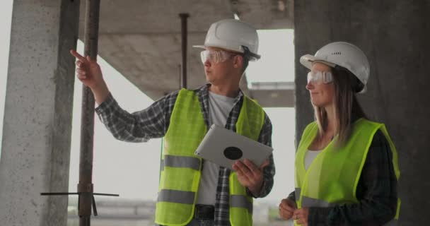 Site de construction Équipe ou architecte et constructeur ou travailleur portant un casque discutent d'un plan de construction d'échafaudage ou d'un plan directeur ou d'une liste de vérification . — Video