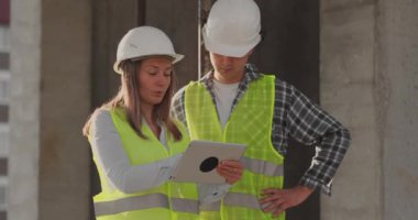 İnşaat sitesi takım veya mimar ve kurucu veya işçi kask ile bir iskele inşaat planı veya plan veya kontrol listesi üzerinde tartışmak.