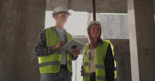 Ingenieurs of architecten hebben een discussie op bouwplaats kijken door het plan van de bouw. Contre Jour. ingenieurs of architecten hebben een discussie. — Stockvideo