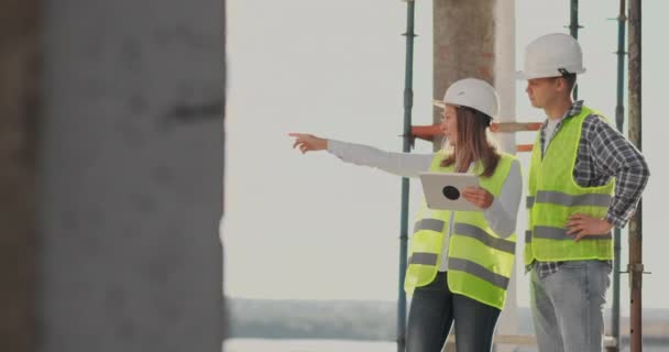 Engenheiros ou arquitetos têm uma discussão no canteiro de obras olhando através do plano de construção. contre jour. Engenheiros ou arquitetos têm uma discussão . — Vídeo de Stock