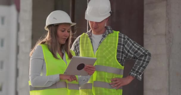 건설 현장에서 태블릿 컴퓨터를 가진 두 명의 엔지니어와 한 여성이 건물의 건설 계획을 비난합니다. — 비디오