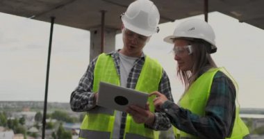 İnşaat işçisi adam ve mimar kadın bir kask içinde evin inşaat planını tartışmak, diğer her bir tablet tutan tasarımı hakkında söyle, çizimler, güneş ışınlarının arka plan bakmak