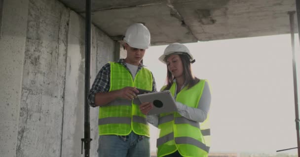工程师设计师站在在建大楼的屋顶上，用平板电脑和手机讨论施工计划和进度 — 图库视频影像
