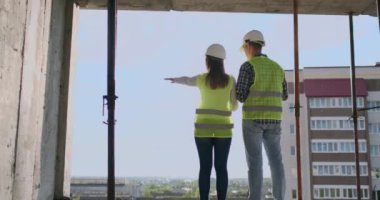 İnşaat alanında çalışan yapı işçileri, planlara bakan inşaatçılar, arka görünüm, kopya alanı. Bina, geliştirme, ekip çalışması ve insan konsepti