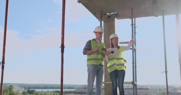 Stavební technika a lidé se usmívající stavitelé v tvrdých kloboucích s počítačem Tablet PC venku. — Stock video