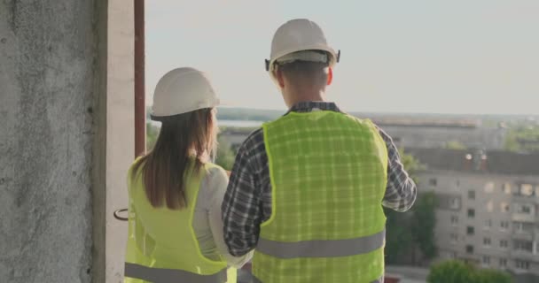 Pareja de ingeniero o técnico hombre y mujer con casco de seguridad celebración de la planificación del teléfono de radio móvil sobre el plan de construcción para saludar proyecto de puesta en marcha en la construcción de la obra, concepto de la industria . — Vídeo de stock