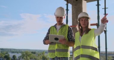 profesyonel güvenlik yeleği mühendisler ve dijital tablet ve planları ile çalışma kask.