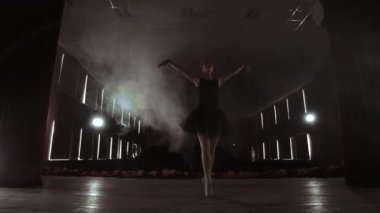 Genç profesyonel balerin sahnede dairesel hareketler yapıyor. Elbise provası sırasında akşam spot ışıkları güzel kız dans