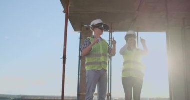 İnşaat sitesi takım veya mimar ve kurucu veya işçi kask ile bir iskele inşaat planı veya plan veya kontrol listesi üzerinde tartışmak.