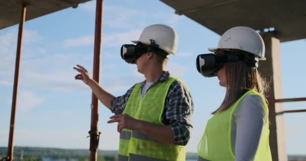 Δύο σύγχρονοι εργαζόμενοι του πληρώματος που χρησιμοποιούν VR για να απεικονίσουν έργα που στέκονται σε ημιτελές κτίριο στο εργοτάξιο, αντίγραφο χώρου. — Αρχείο Βίντεο