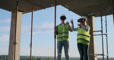 İnşaat sitesi takım veya mimar ve kurucu veya işçi kask ile bir iskele inşaat planı veya plan veya kontrol listesi üzerinde tartışmak.