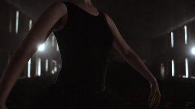 Orta plan yavaş hareket: genç bir balerin kız karanlık ve duman bir tutu ve Pointe Ayakkabı sahnede zarif hareketler gerçekleştirir