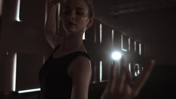Mulher graciosa bailarina em um vestido escuro em um palco escuro do teatro na fumaça executa movimentos de dança em câmera lenta — Vídeo de Stock
