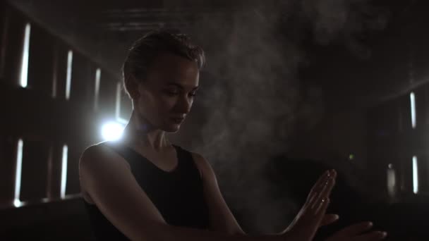 Middle plan slow motion: a Young ballerina girl performs graceful movements on the stage in a tutu and Pointe shoes in the dark and smoke — Stock Video