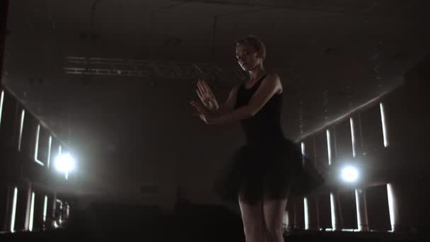 Femme gracieuse ballerine dans une robe sombre sur une scène sombre du théâtre dans la fumée effectue des mouvements de danse au ralenti — Video