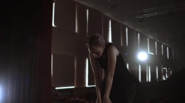 Orta plan yavaş hareket: genç bir balerin kız karanlık ve duman bir tutu ve Pointe Ayakkabı sahnede zarif hareketler gerçekleştirir