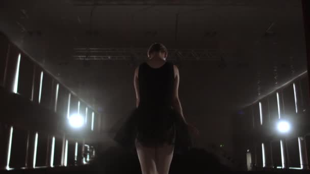 Close-up de bailarina de balé como ela pratica exercícios em palco escuro ou estúdio. A bailarina mostra o clássico ballet pas. Movimento lento. Inflamação, tiro de gimbal — Vídeo de Stock